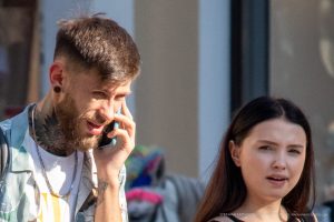 Фото тату на шее и руке мужчины, говорящего по телефону, уличный стиль, современная татуировка.
