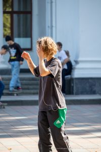 Фотография молодого человека на скейтборде с татуировкой на руке. Уличная татуировка, современный стиль, активный образ жизни.