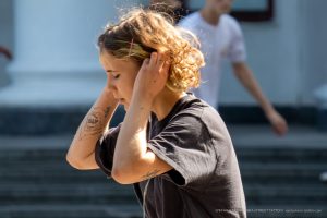 Фотография девушки с татуировкой на предплечье, смотрящей в сторону. Уличная татуировка, современный стиль, портретная фотография.