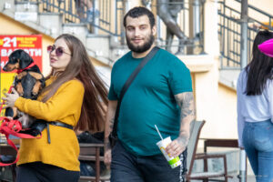 Фото мужчины с татуировкой на предплечье и собакой породы такса. Детализированный рисунок татуировки в стиле олдскул.