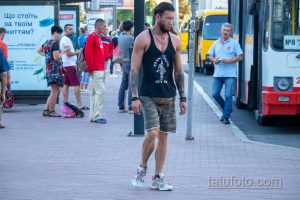 Фото тату: мужчина с татуировкой на руке, демонстрирующий свою спортивную форму. Татуировка выполнена в черных тонах и изображает воина.