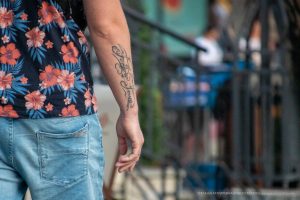 Фото татуировки на руке мужчины, представляющей собой надпись, выполненную в стиле каллиграфии. Черные чернила, изящный шрифт.