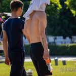 Фото тату: мужчина с черной надписью на предплечье, идущий по парку в солнечный день. Татуировка выполнена каллиграфическим шрифтом.