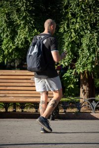 Фото тату на теле мужчины: татуировки на шее, предплечье и ногах, выполненные в разных стилях. Уличная фотография.