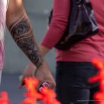 Фото тату на руке: реалистичный портрет льва с открытым глазом, выполненный в черно-серых тонах. Детализированный рисунок татуировки.