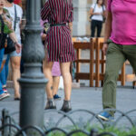 Фото татуировки в виде цветка на ноге девушки, одетой в полосатое платье. Видны детали рисунка и летняя обстановка.