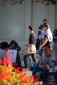 Фото тату: мужчина с татуировкой на руке, стоящий на улице. Черно-белый рисунок татуировки, детализированный и стильный. Фотография сделана на фоне городской архитектуры.