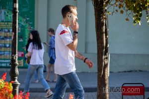 Фото мужчины с татуировками на предплечье, разговаривающего по телефону. Видны детализированные рисунки татуировок в различных стилях.