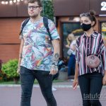 Фото мужчины с татуировками на предплечье и шее. Видны детализированные рисунки татуировок в стиле олдскул и графика.