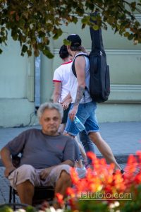 Фотография мужчины с татуировкой волка на руке, идущего по улице. Тату выполнено в реалистичном стиле и занимает большую часть предплечья.