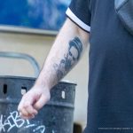 Фото татуировки портрета на руке мужчины. Рисунок выполнен в черно-белой гамме, с высокой детализацией. Видны черты лица и выражение эмоций.