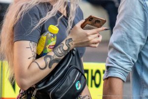 Фото тату на руке девушки: длинная змея, обвивающая руку, выполнена в черно-серых тонах. Детализированный рисунок татуировки выглядит эффектно и стильно.