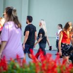 Фотография пары, идущей по улице, у девушки на руке видна татуировка, а мужчина держит ее за руку.