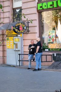 Фото мужчины с татуировкой на руке, уличный стиль. На руке изображена детальная татуировка с виноградной лозой и гроздьями.