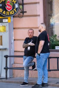 Фото мужчины с татуировкой на руке, общее фото. На руке изображена детальная татуировка с виноградной лозой и гроздьями.