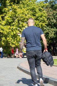 Фото мужчины с татуировкой на руке, вид сзади. На руке изображена детальная татуировка с виноградной лозой и гроздьями.