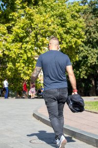 Фото мужчины с татуировкой на руке, вид сзади. На руке изображена детальная татуировка с виноградной лозой и гроздьями.