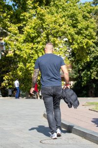 Фото мужчины с татуировкой на руке, вид сзади. На руке изображена детальная татуировка с виноградной лозой и гроздьями.