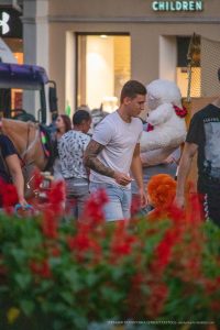 Фотография мужчины с татуировкой на руке, идущего по улице. Татуировка выполнена в темных тонах и занимает большую часть предплечья.