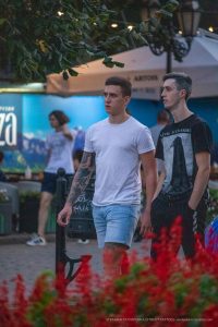 Фотография двух мужчин, один из которых имеет татуировку на руке. Татуировка выполнена в темных тонах и занимает большую часть предплечья.