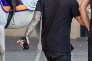 Крупный план руки мужчины с татуировкой в виде цветка и листьев. Татуировка выполнена в черно-серых тонах, с высокой детализацией.