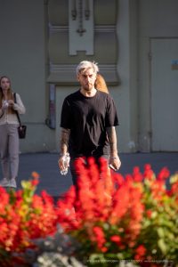 Фотография мужчины с татуировкой на руке и минималистичной татуировкой на шее. Изображение демонстрирует сочетание разных стилей татуировок.