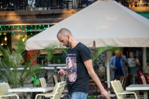Фото тату на шее мужчины: реалистичное изображение женского лица, темная футболка, уличный стиль, портретная татуировка.