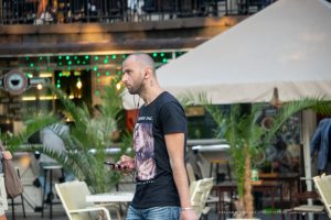 Фото тату на шее мужчины: реалистичное изображение женского лица, темная футболка, уличный стиль.