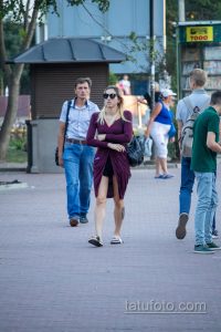 Фотография девушки в платье с татуировкой на ноге. Современный городской стиль, летняя прогулка.