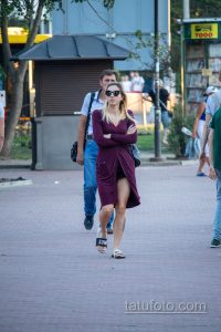 Фотография девушки в платье с татуировкой на ноге. Современный городской стиль, летняя прогулка.