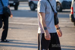 Фото тату: мужчина с татуировкой в виде леса на руке, идущий по улице.