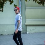 Фото мужчины с татуировками на руках, шее и плечах, в кепке и очках, уличный стиль.