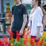 Фотография мужчины с татуировкой на предплечье, идущего рядом с девушкой. Татуировка выполнена в реалистичном стиле с изображением птицы и цветов.