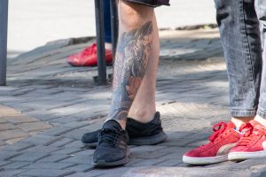 Фото тату: цветная татуировка карпа кои на икре мужчины. Детализированный рисунок в японском стиле с использованием ярких цветов и традиционных элементов.