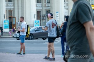 Фотография мужчины с татуировкой на ноге, одетого в летнюю одежду. Видна часть татуировки, выполненной в темных тонах.