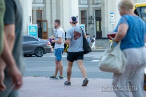 Фотография мужчины с татуировкой на ноге, одетого в летнюю одежду. Видна часть татуировки, выполненной в темных тонах.