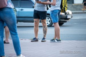 Крупный план татуировки на ноге, изображающей сложный растительный орнамент с элементами японской культуры. Видны детализированные линии и тени.