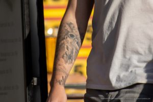 Фото тату: крупный план черно-серой татуировки космонавта в скафандре на руке. Детализированный рисунок с проработкой деталей скафандра и космического фона.