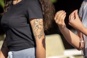 Фото татуировки с изображением цветка на руке девушки. Детализированный рисунок, черно-белая гамма, графический стиль.