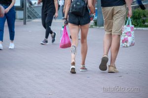Фото тату на икре: карп кои с цветами, выполненный в черно-белой гамме. Детализированный рисунок, плавные линии, динамичная композиция.