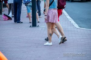 Фотография татуировки Дэдпула на ноге девушки. Черно-белый рисунок в стиле комиксов, изображающий персонажа в динамичной позе.