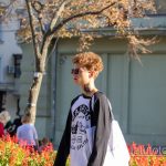 Фото молодого человека с татуировкой на шее, одетого в куртку и очки. Черный рисунок татуировки в стиле минимализм.