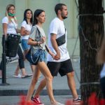Фотография пары, идущей по улице. У мужчины видна татуировка на руке, а у девушки - на ноге.