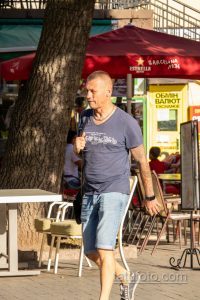 Фото тату на руках мужчины, гуляющего по улице. Рукава полностью покрыты сложным рисунком татуировки в темных тонах.