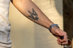 Фото тату на предплечье мужчины: стилизованное изображение головы волка, выполненное в геометрическом стиле. Эскиз татуировки выполнен в черном цвете.