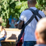Фото тату на предплечье мужчины, выполненное в черных тонах с элементами красного. Детализированный рисунок с абстрактными формами и брызгами краски.