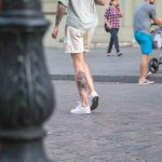 Фотография мужчины, идущего по улице с видимой татуировкой на бедре. Татуировка выполнена в ярких цветах и изображает тигра и цветы.
