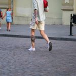 Фотография мужчины, идущего по улице с видимой татуировкой на бедре. Татуировка выполнена в ярких цветах и изображает тигра и цветы.