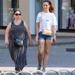 Фотография девушки, идущей по улице с видимой татуировкой на бедре. Татуировка выполнена в черно-белых тонах и изображает цветы и тигра.