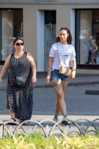 Фотография девушки, идущей по улице с видимой татуировкой на бедре. Татуировка выполнена в черно-белых тонах и изображает цветы и тигра.